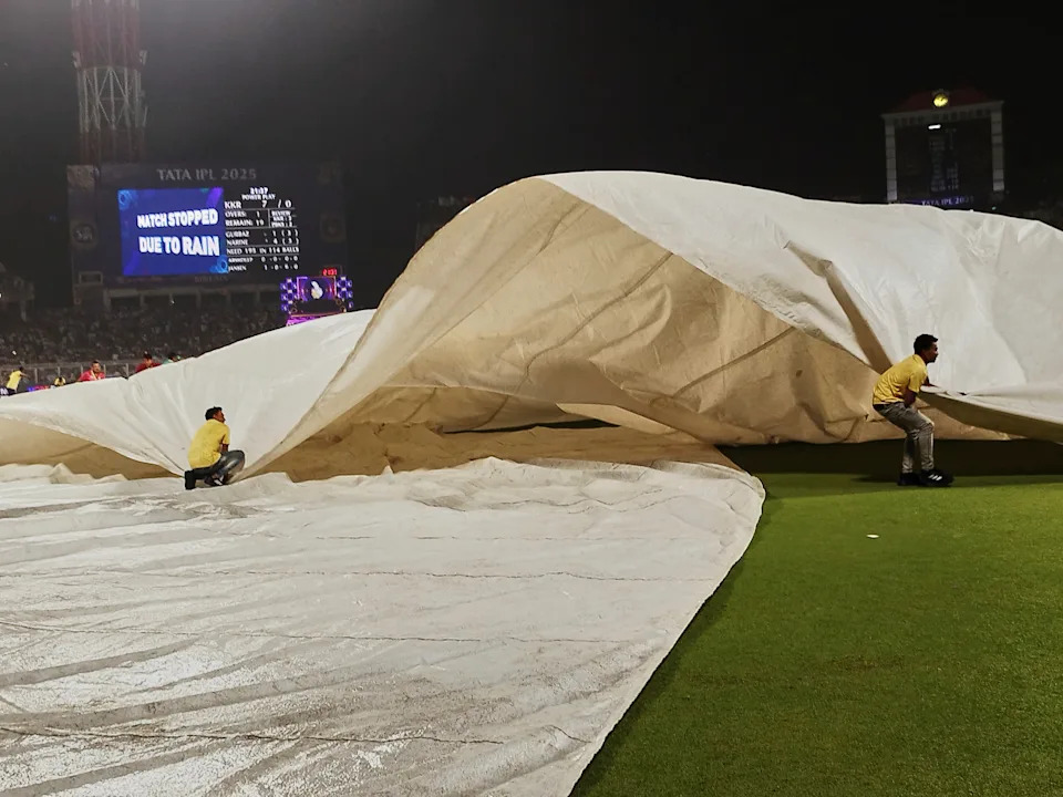 Players and ground staff securing the pitch during rain in the Punjab Kings vs Kolkata Knight Riders match scorecard scene, Eden Gardens, IPL 2025