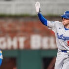 A packed MLB stadium with Dodgers and Atlanta Braves fans cheering at night.