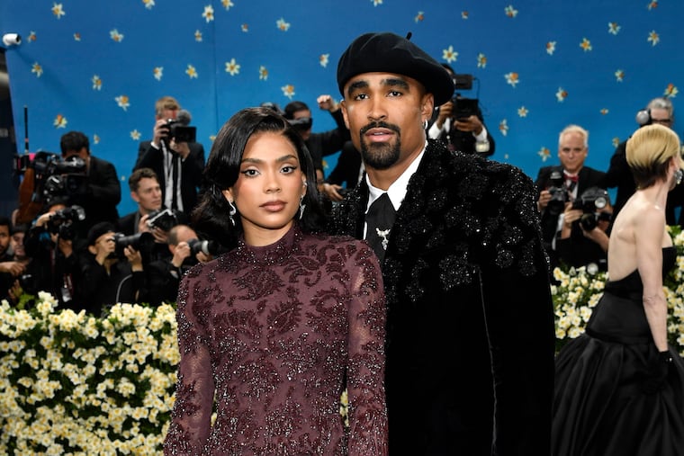 Jalen Hurts and Bry Burrows at the Met Gala 2025, both dressed in designer black tie, making an entrance on the steps.