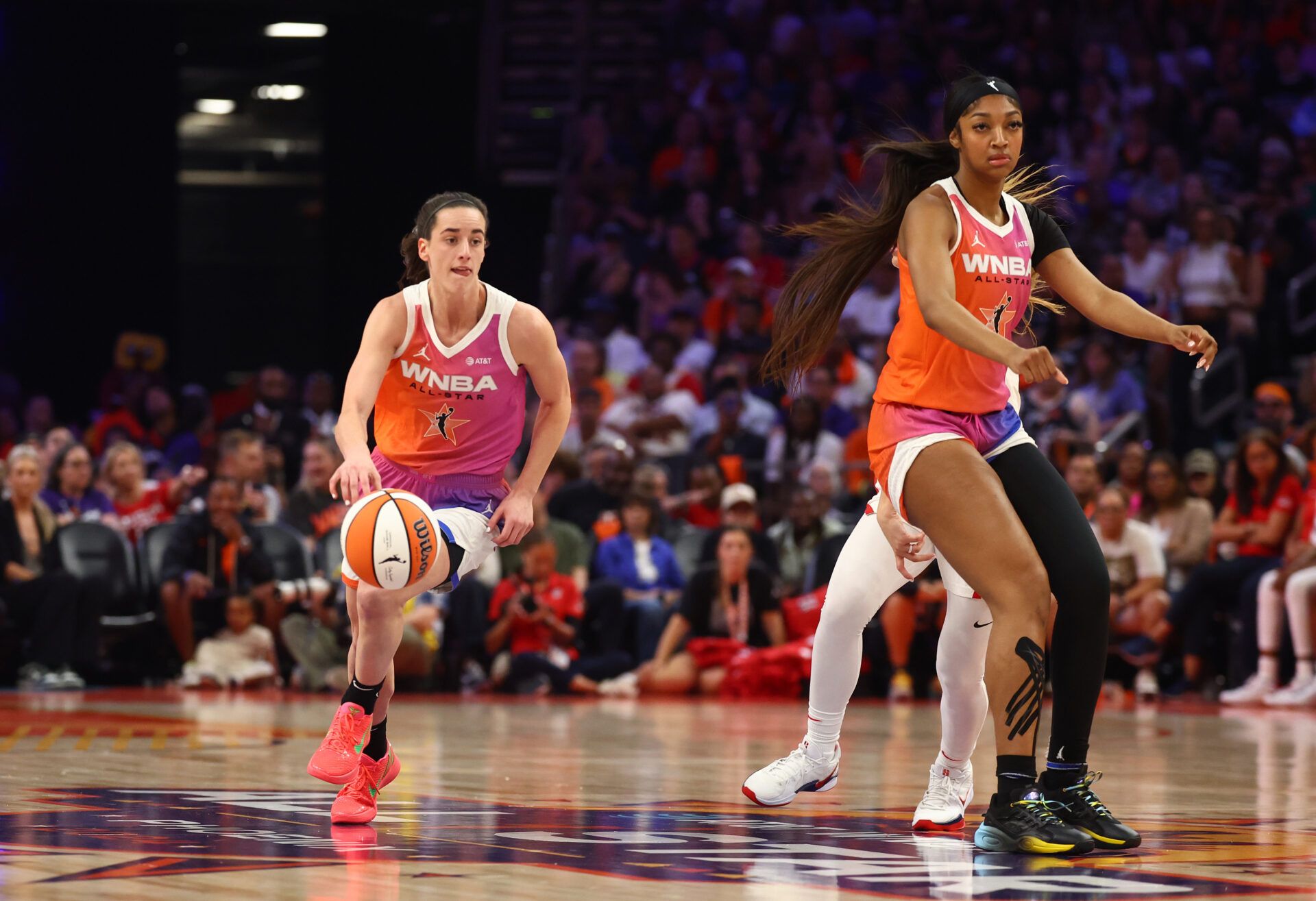 Caitlin Clark net worth: smiling and holding a basketball during a WNBA game