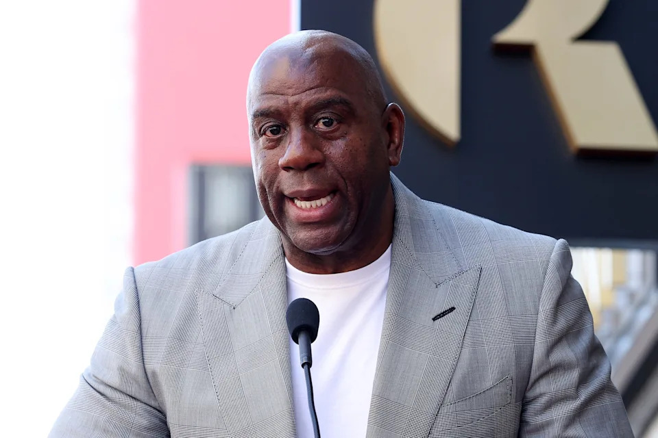 Magic Johnson looking on during a Lakers game, symbolizing his enduring influence on the NBA.
