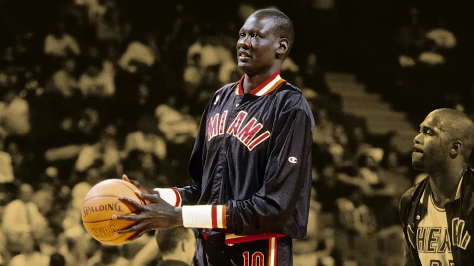 Manute Bol towering over shorter players on the basketball court