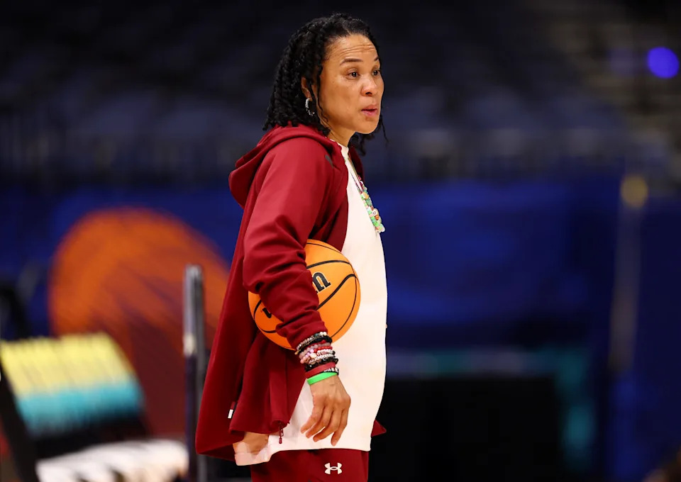 Dawn Staley courtside during a basketball game, exemplifying leadership and focus
